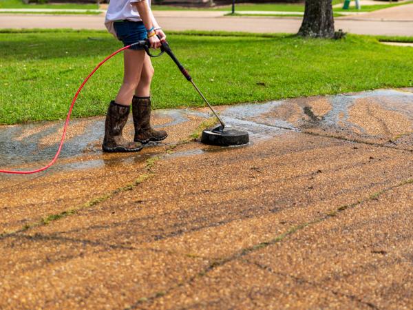 Woman pressure washing driveway