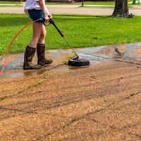 Woman pressure washing driveway