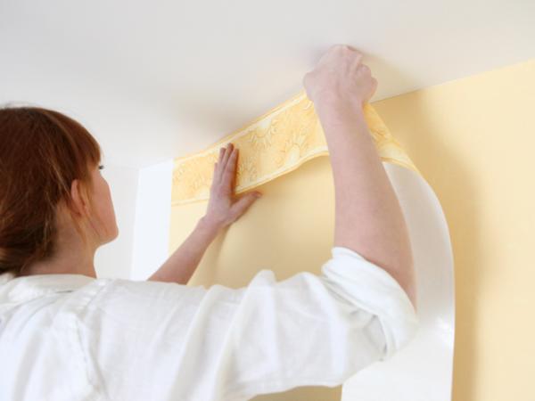 Woman installing wallpaper border